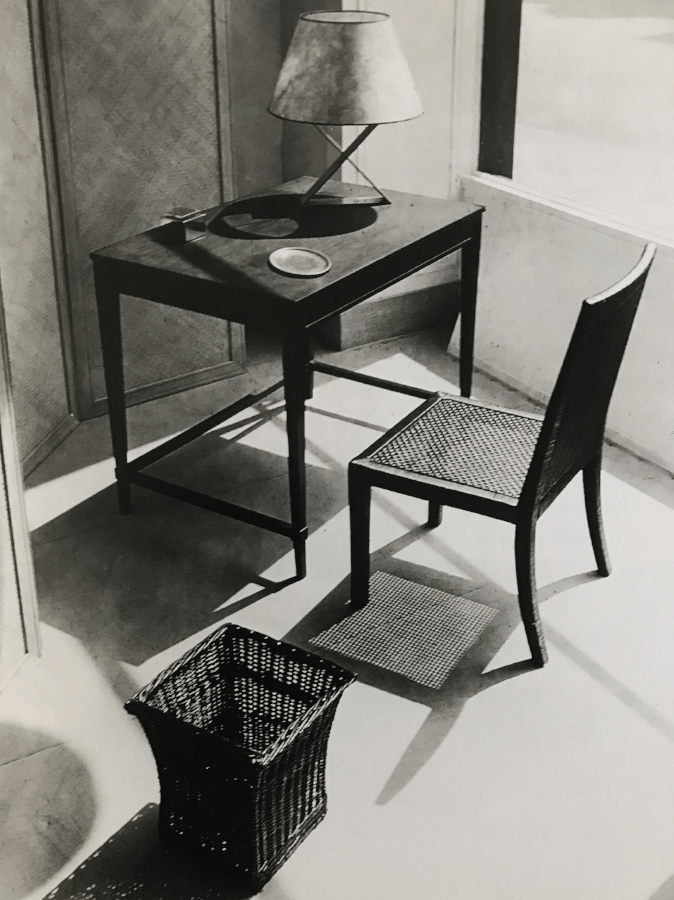 Window display at the Jean-Michel Frank boutique, circa 1935. Dark stained wood lady's desk with plinth legs, chair and basket in woven wicker, the X lamp in metal.