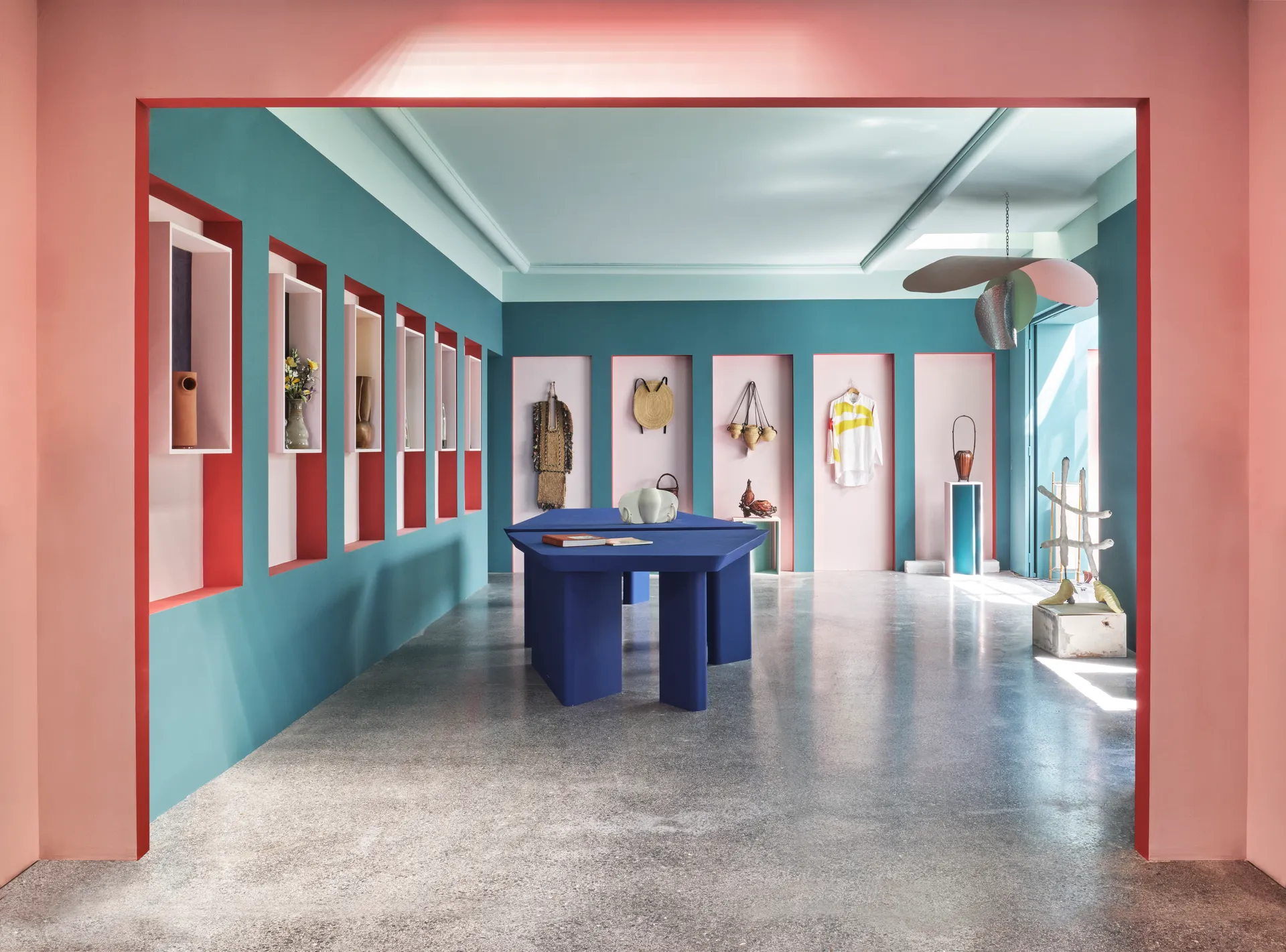 A retail space uses pink, blue, and red to color block, highlighting specific items on the walls