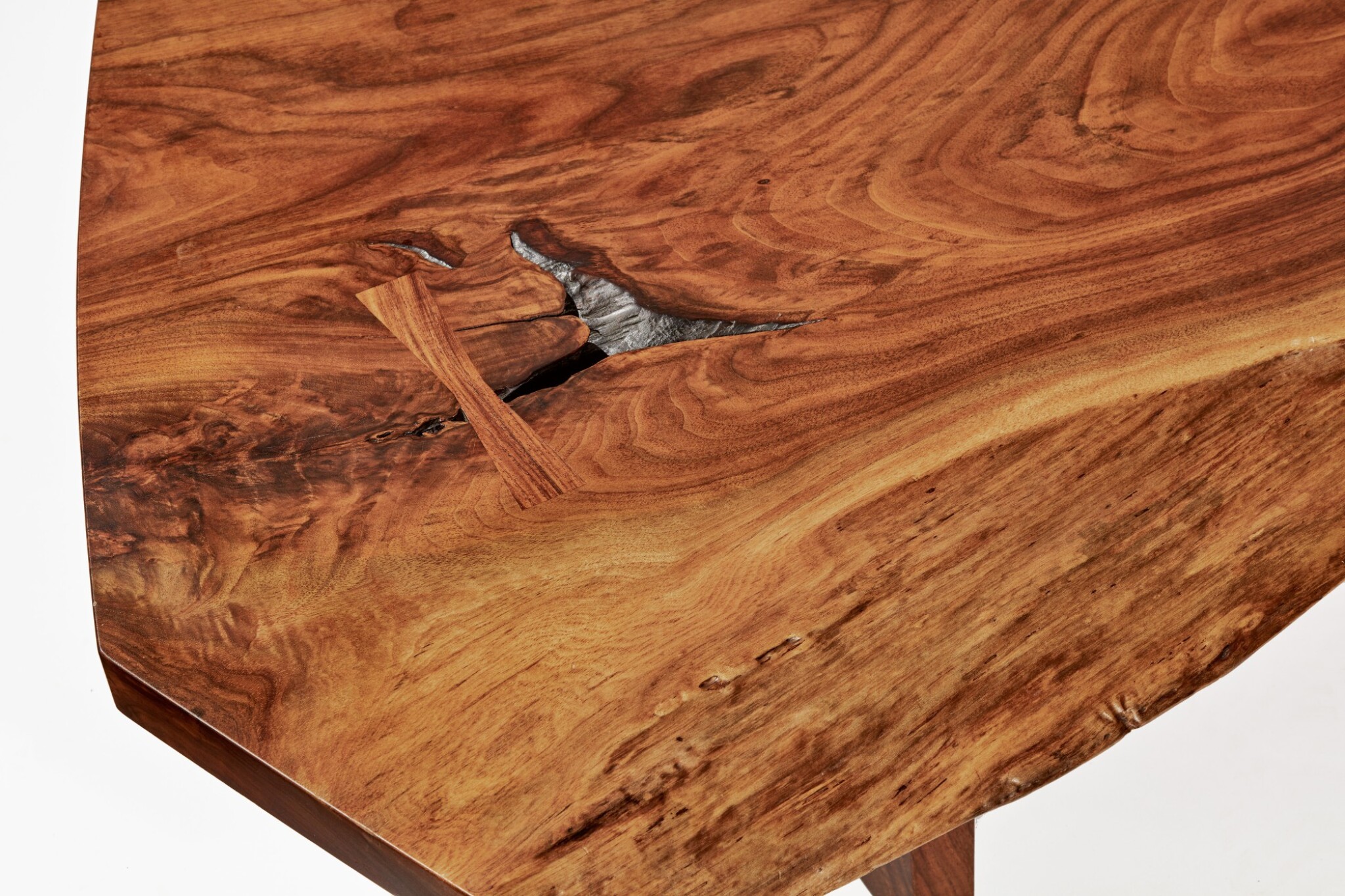 A close-up of Nakashima's 1985 Conoid Slab Coffee Table displays the intricate woodworking required to pull off his signature butterfly joint